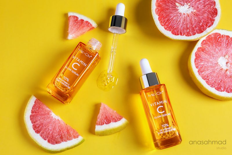 Meon Vitamin C glow serum bottles styled with fresh grapefruit
