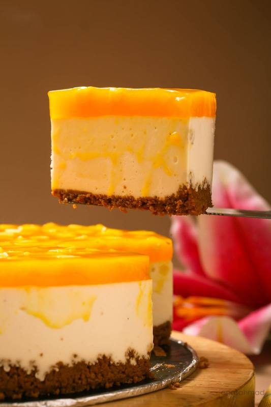 Mango cheesecake slice with glossy mango glaze lifted from the whole cake