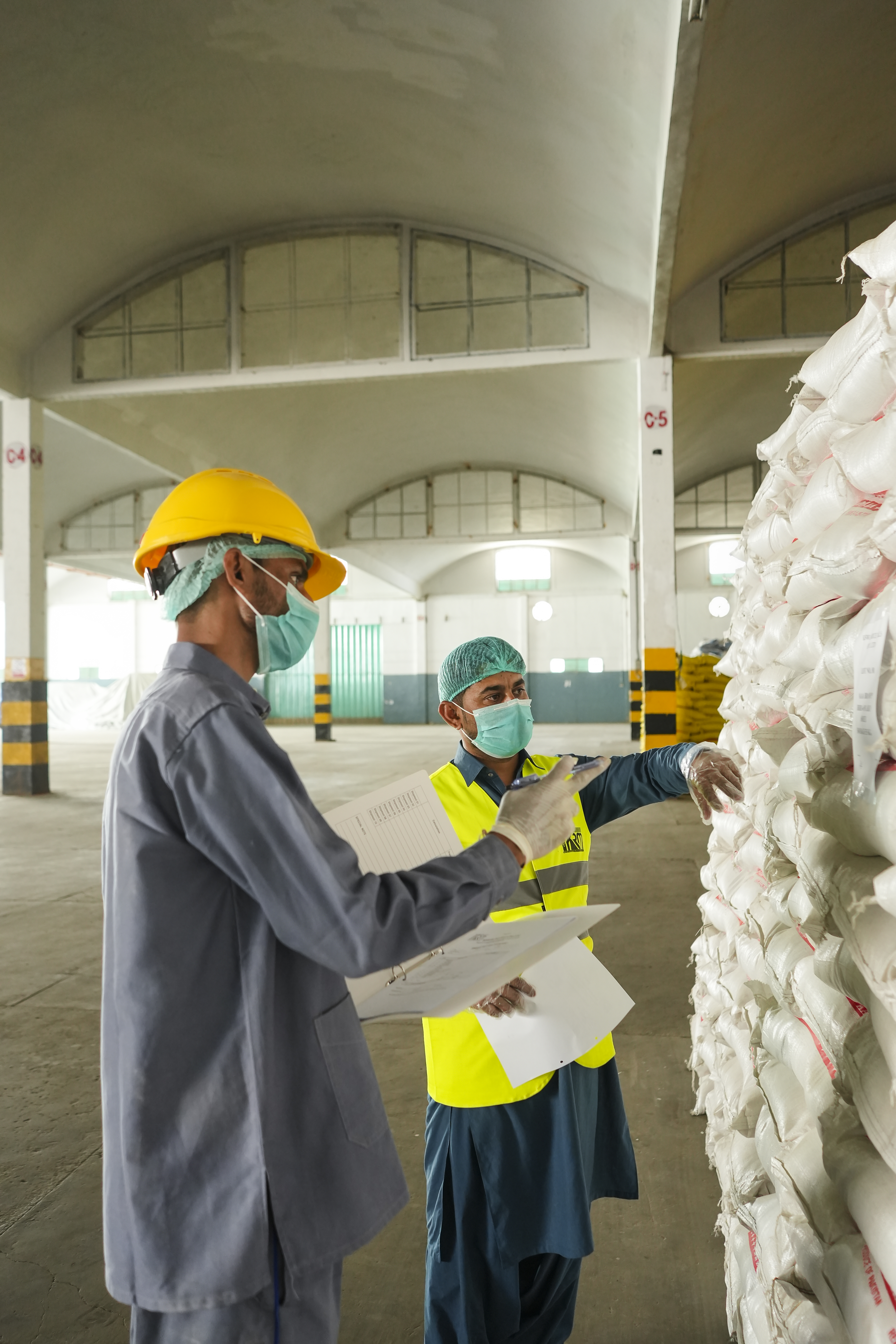Factory workers wearing safety helmets and masks inside production area