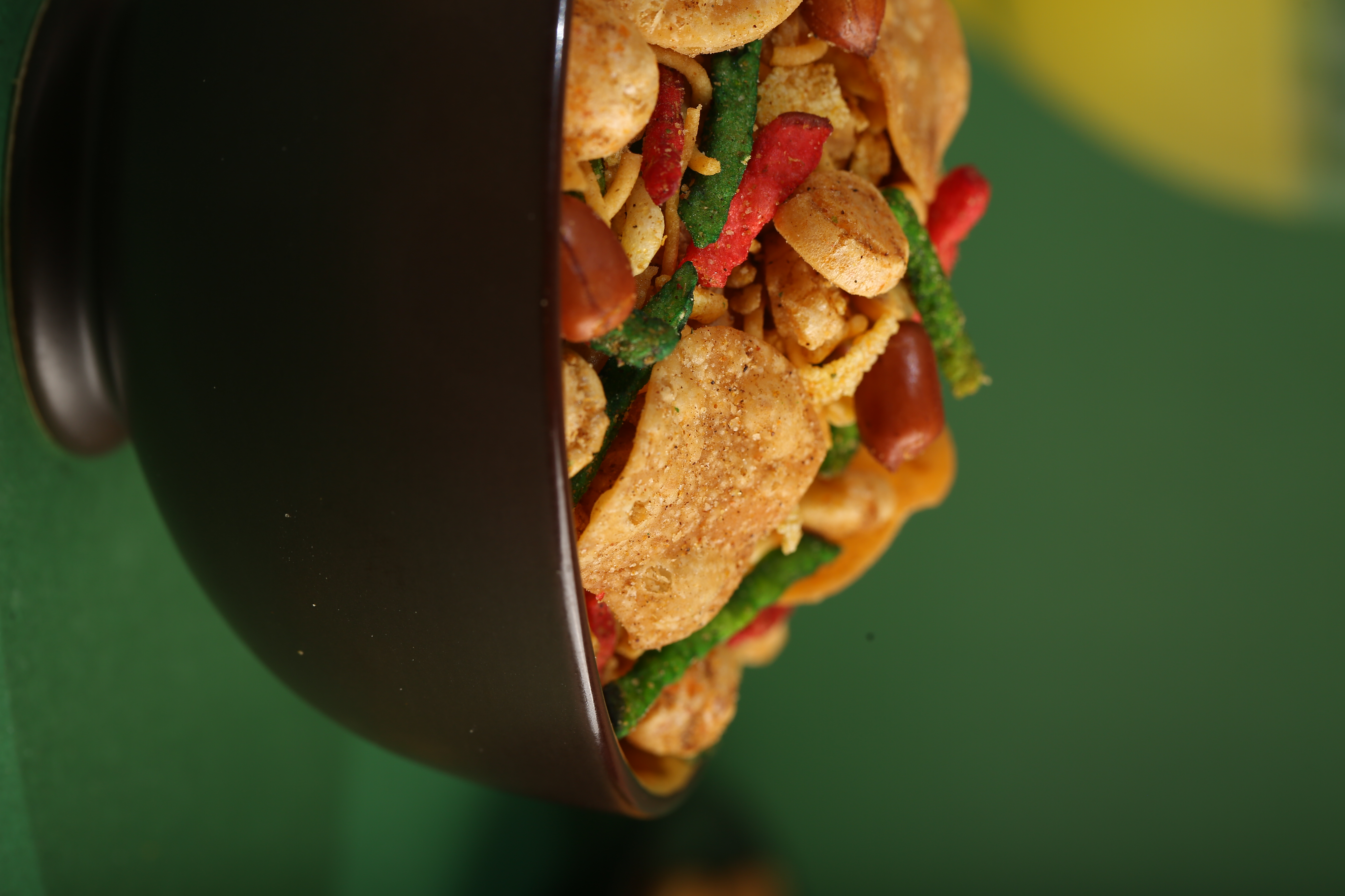 Colorful crunchy snack mix with chips, peanuts, and spices spilling from a bowl
