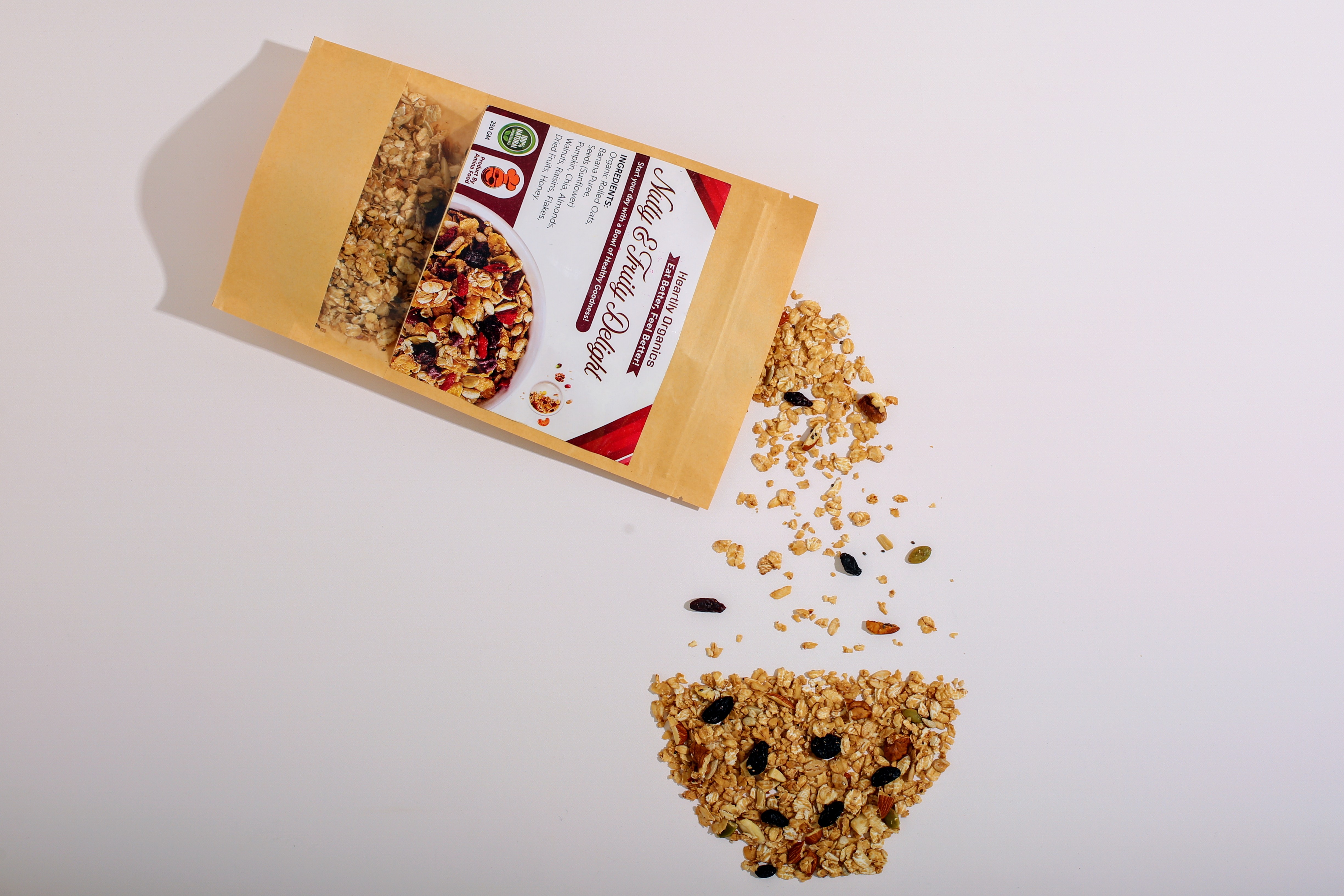 Healthy granola mix spilling from a kraft paper pouch with nuts and dried fruits