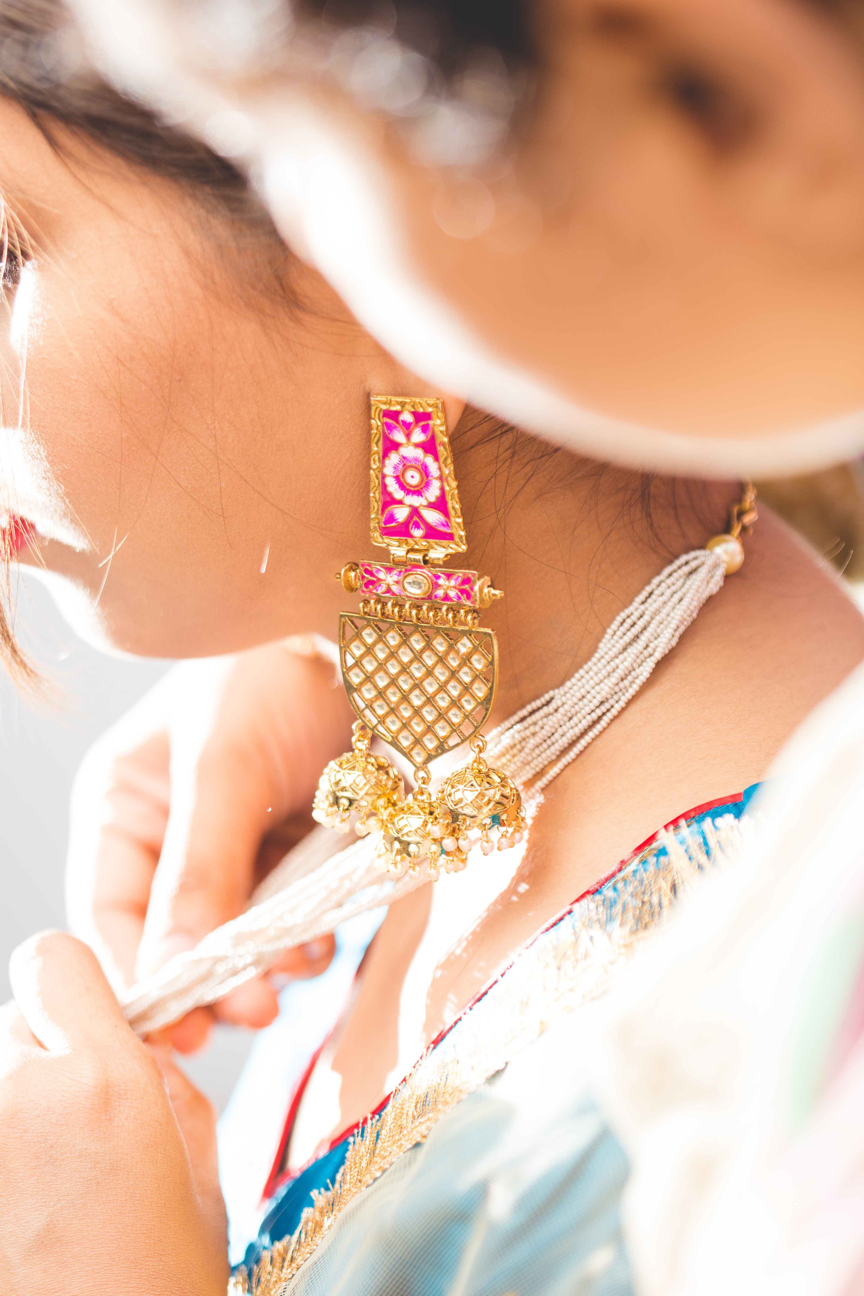 Traditional gold and pink jhumka earring worn by woman with intricate design